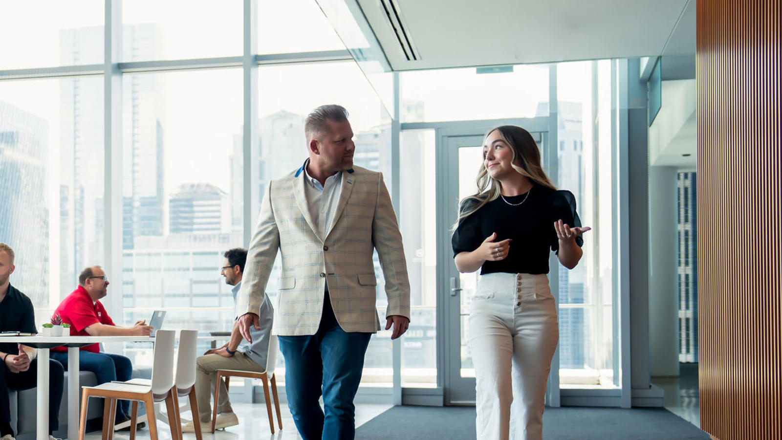 a man and woman walking in a room with windows