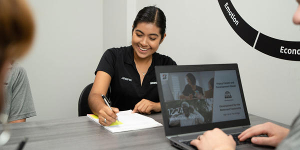 a woman sitting at a table writing on a piece of paper