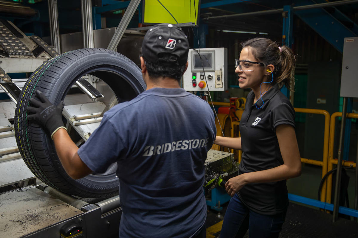 a man and woman standing next to a tire