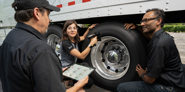 a group of people standing around a truck tire