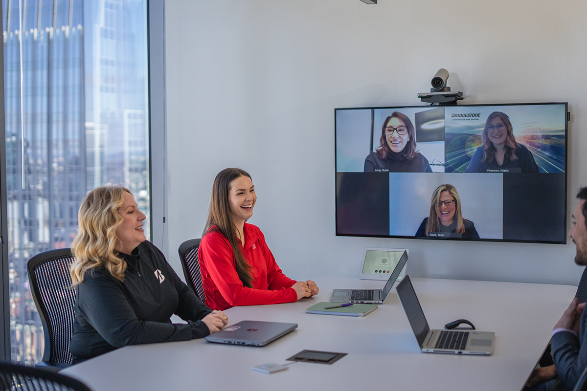 a group of women sitting at a table with laptops and video conferencing