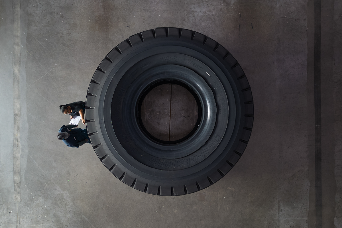 a man standing behind a large tire