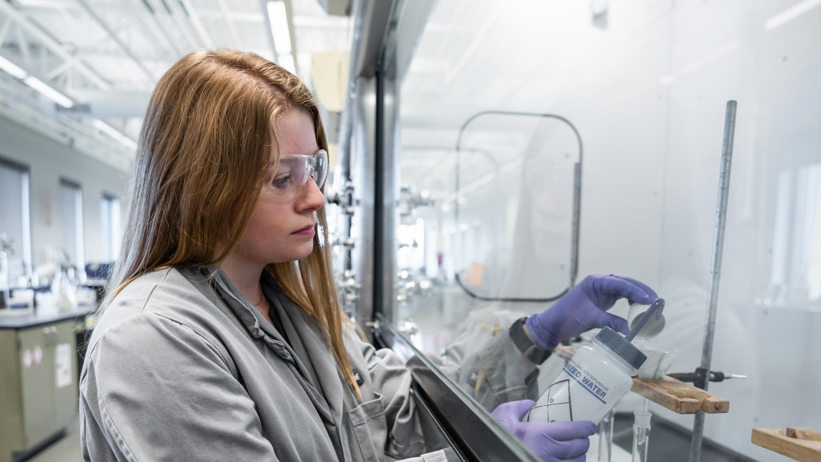 a woman wearing goggles and gloves looking at a bottle