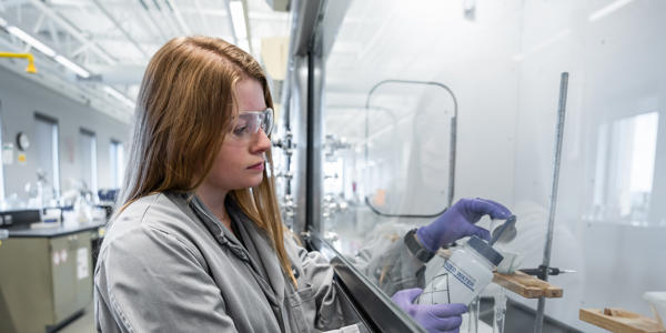 a woman wearing goggles and gloves looking at a bottle