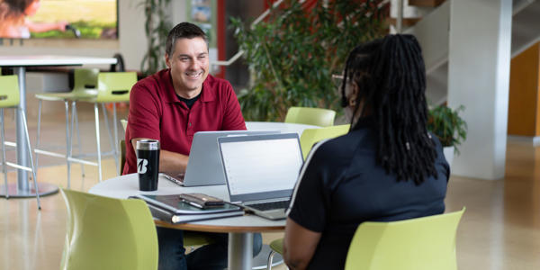 a man and woman sitting at a table with laptops