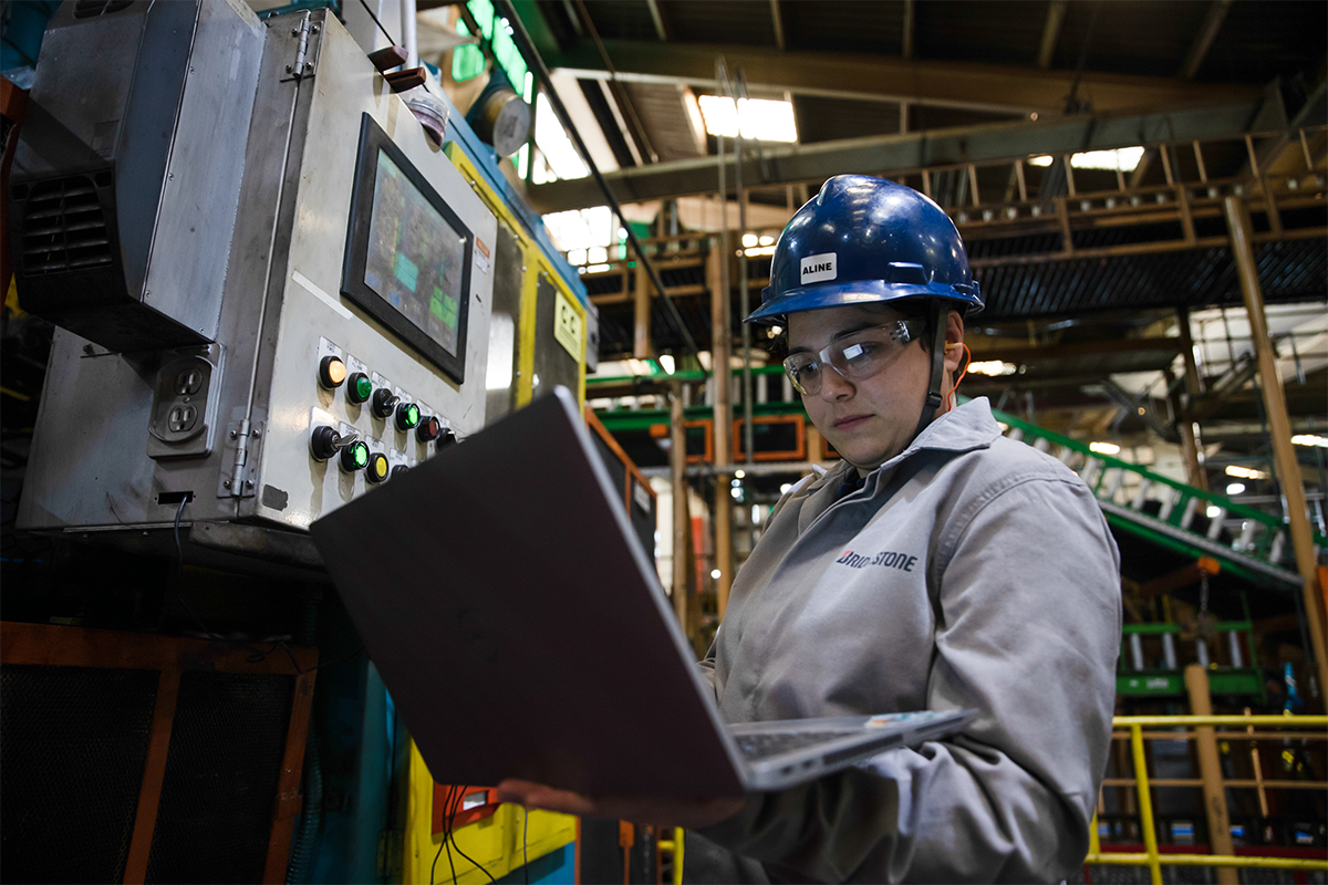 a man wearing hard hat and glasses holding a laptop