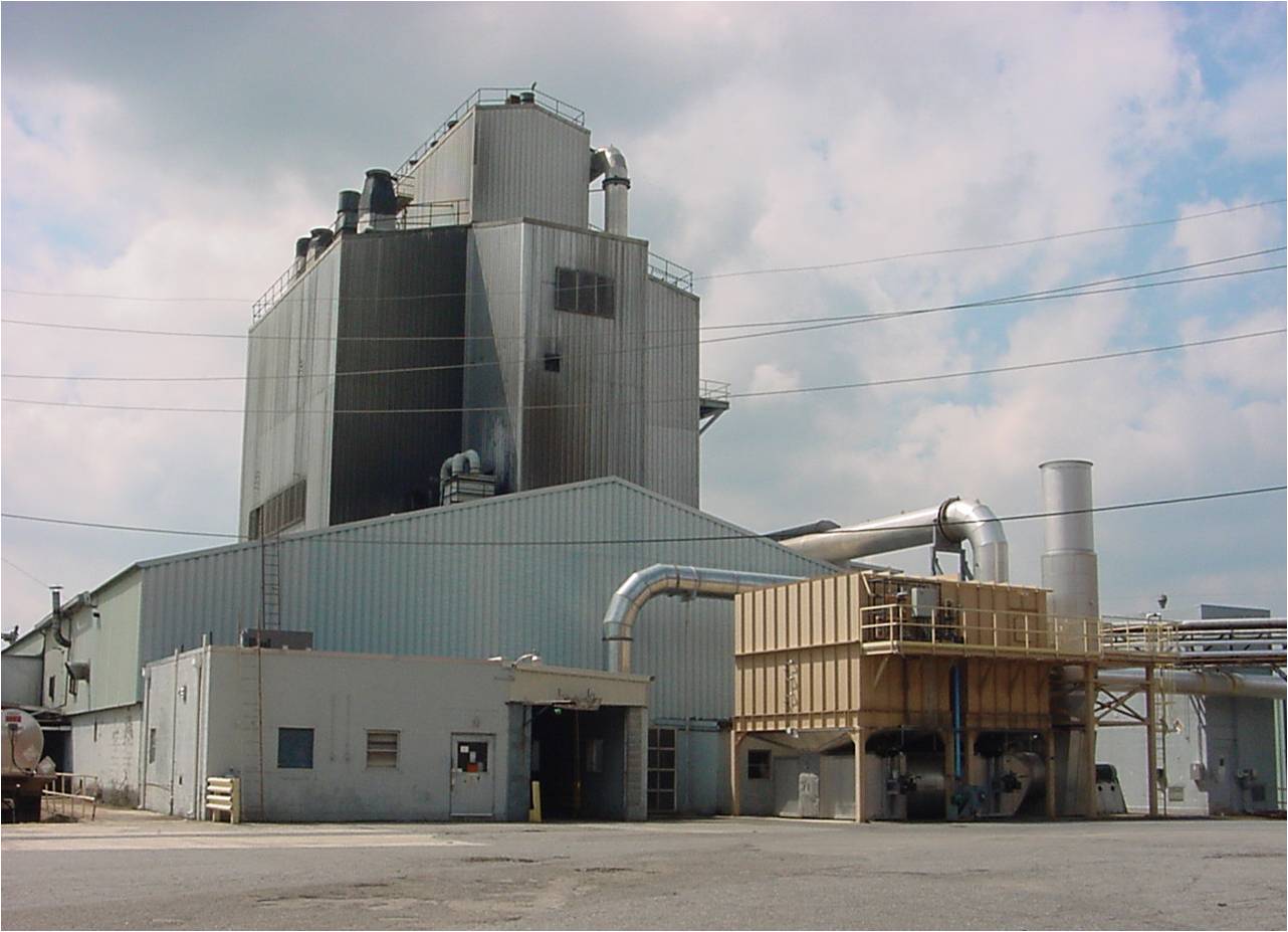 a large factory with a few pipes with Weisman Art Museum in the background