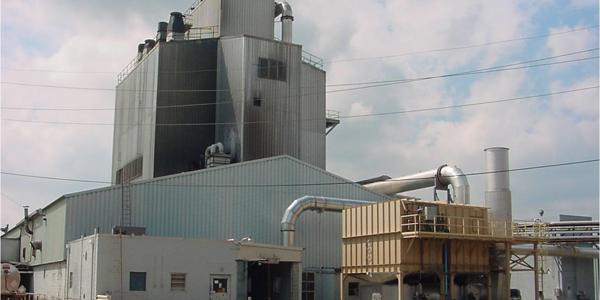 a large factory with a few pipes with Weisman Art Museum in the background