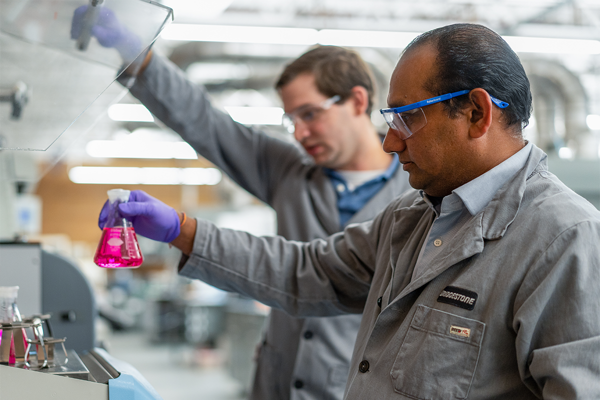 a man holding a flask with a pink liquid in it