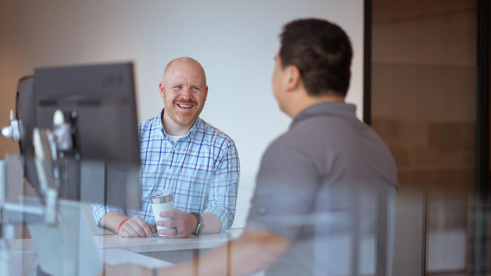 a man sitting at a table with another man in the background