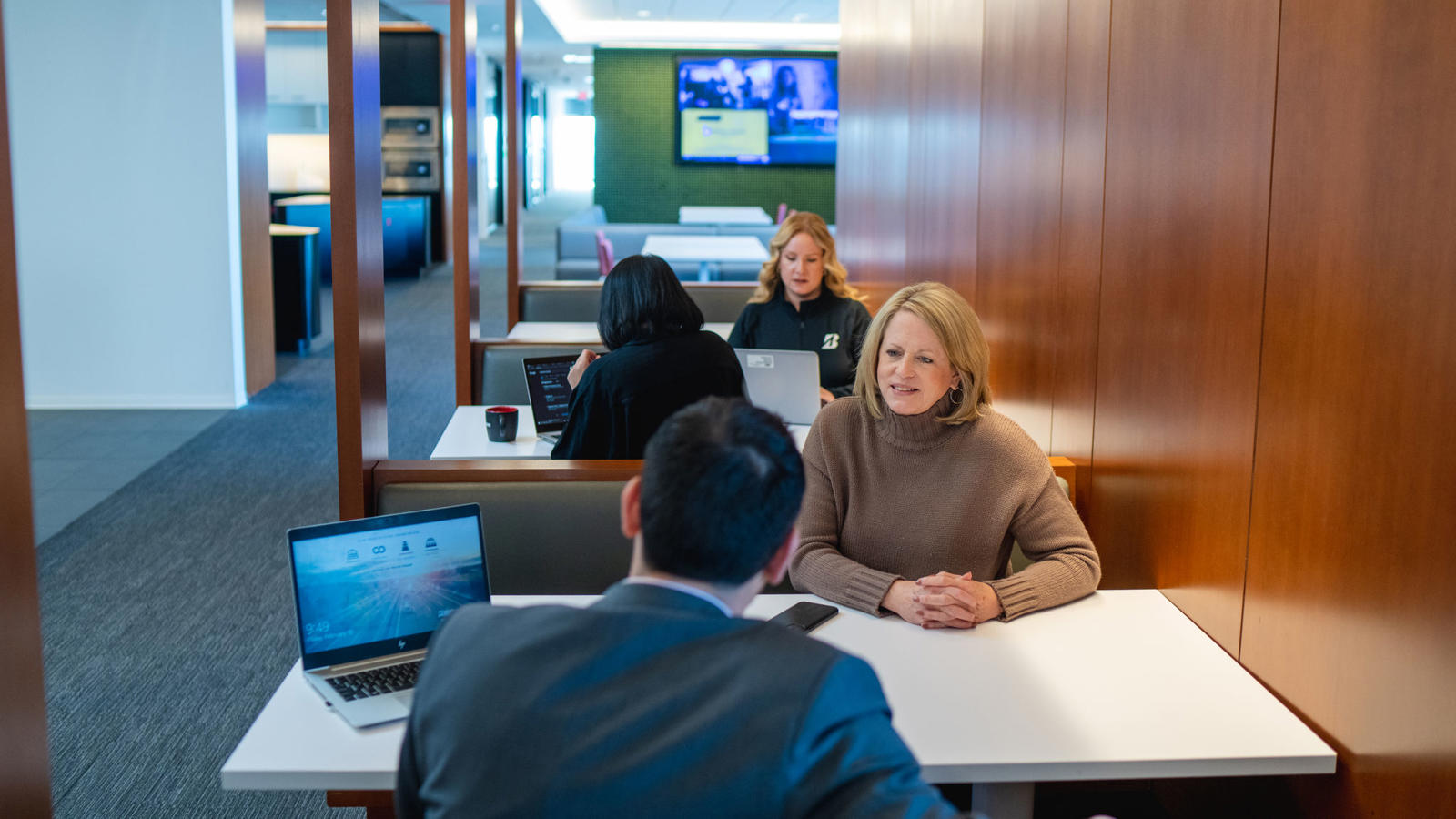 a group of people sitting at a table with laptops