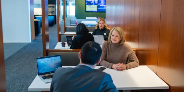 a group of people sitting at a table with laptops