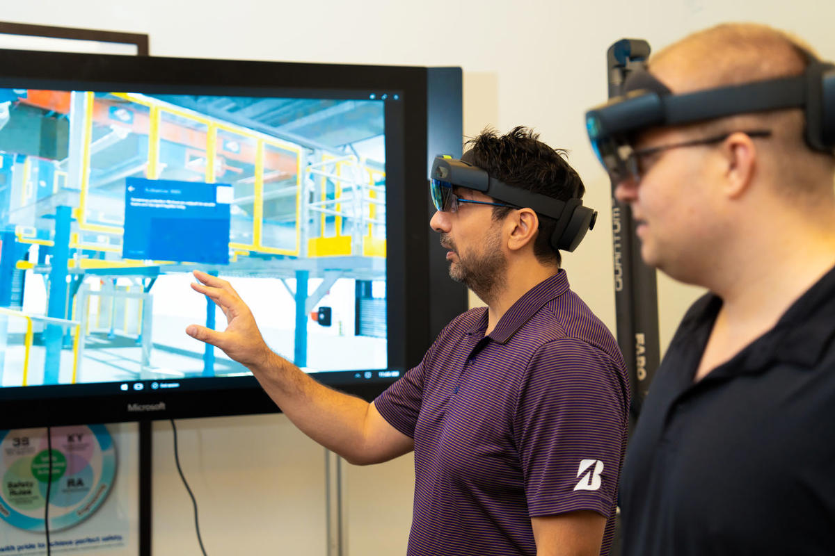 a man wearing virtual reality goggles pointing at a screen